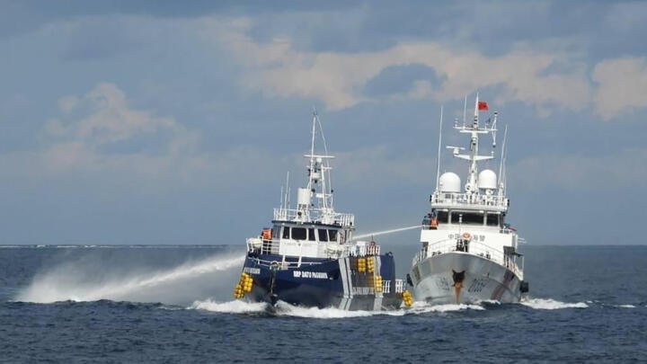 This handout photo taken and released on October 12, 2025 by the Philippine Coast Guard shows a China Coast Guard ship (R) deploying water cannon as a Philippine Bureau of Fisheries vessel (L) is seen