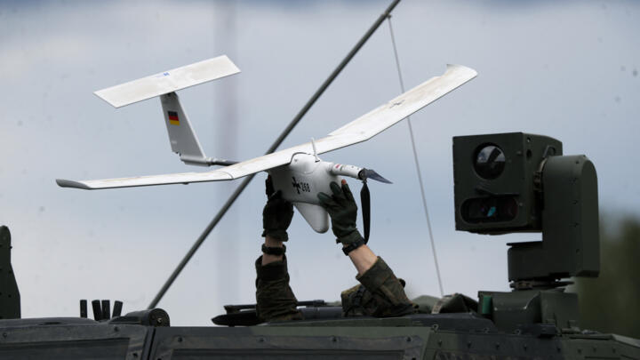 A soldier holds a drone atop of a NATO military vehicle rolling during a military exercising at the Training Range in Pabrade, some 60km north of the capital Vilnius, Lithuania on June 26, 2023.