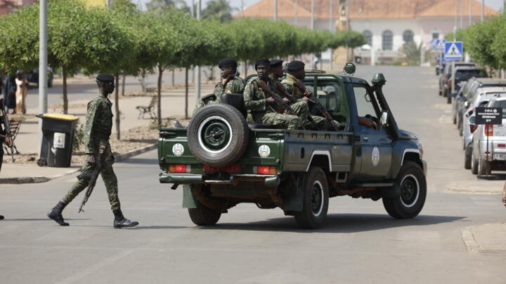 Soldiers hold weapons while patrolling a street near the scene of gunfire near the Presidential Palace in Bissau on November 26, 2025.