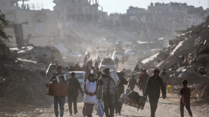 Palestinians carry their belongings as they return to Rafah in southern Gaza, surrounded by destruction.