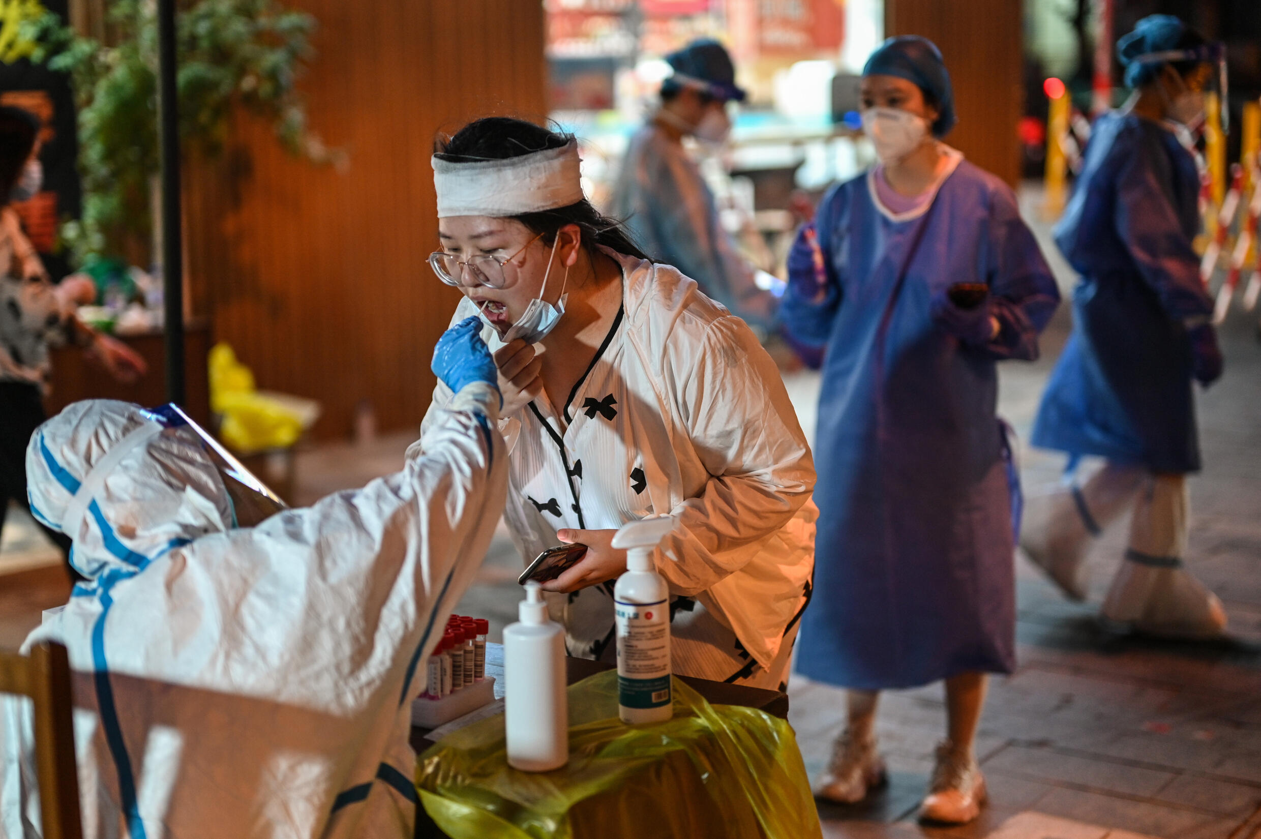 Una mujer se deja tomar una muestra de saliva para realizar una prueba de detección del coronavirus, el 12 de julio de 2022 en la ciudad china de Shanghái