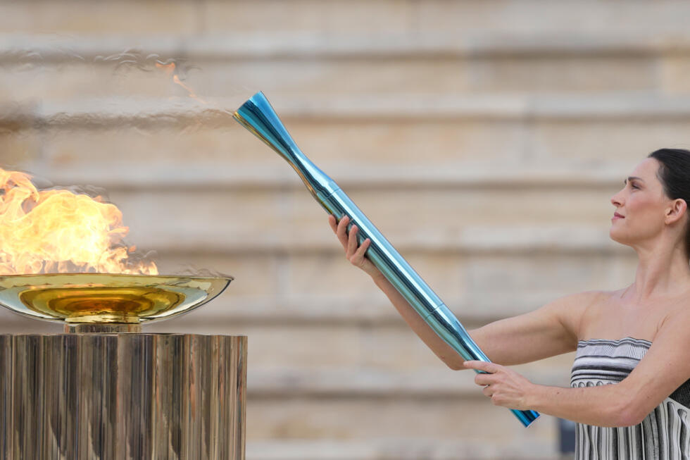 Greek actress Mary Mina, playing the role of the High Priestess, lights a torch during the torch relay ceremony for the Milan Cortina 2026 Winter Olympics at the Panathinaiko Stadium in Athens.