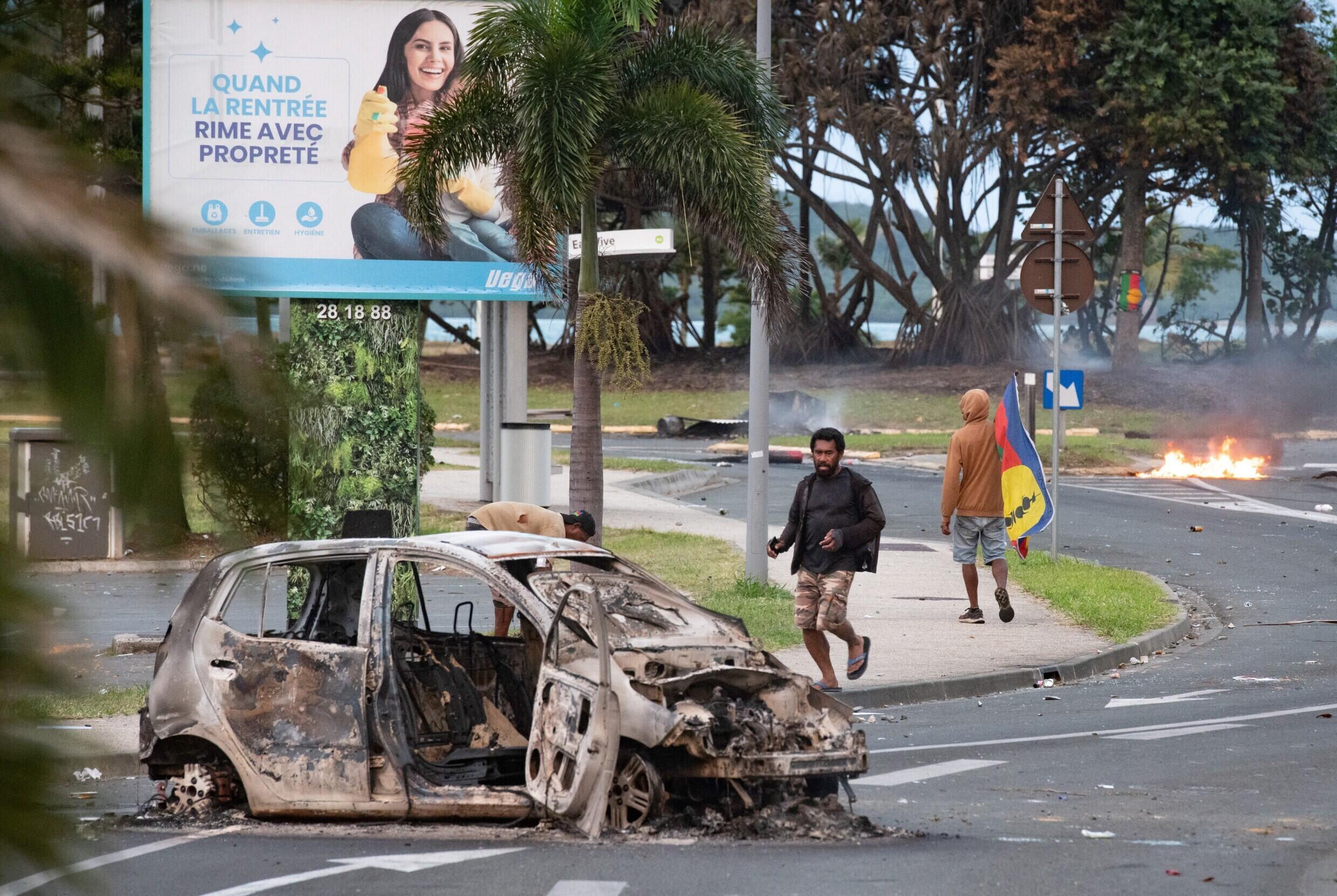 Les restes d'une voiture brûlée gisent dans une rue du quartier N'Gea à Nouméa, le 14 mai 2024, après le déclenchement de violentes émeutes contre l'adoption d'une réforme constitutionnelle visant à élargir le corps électoral en Nouvelle-Calédonie.