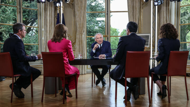 France's Prime Minister Francois Bayrou (C) speaks with journalists during a live televised interview broadcast with news channels LCI, CNews, BFMTV, and FranceInfo TV, at the Hotel de Matignon in Par