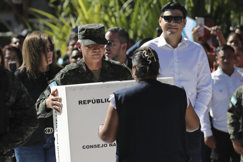 El jefe del Estado Mayor Conjunto de las Fuerzas Armadas de Honduras, el general Roosevelt Hernández (c), sostiene una caja con material electoral en el acto de su distribución para las elecciones generales del 30 de noviembre.
