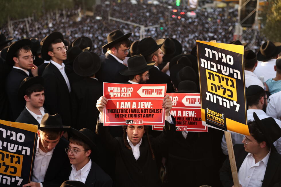 An ultra-Orthodox Jewish man holds up a placard during a protest against conscription.