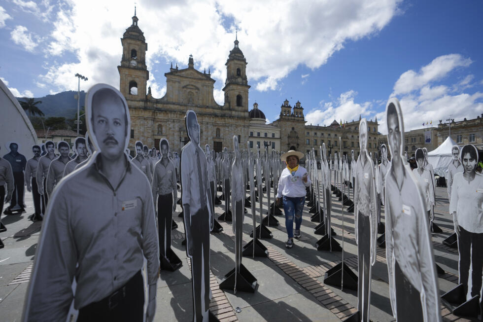 Archivo: Matilde Fomeque, esposa de Mario Barón, miembro asesinado del partido político Unión Patriótica (UP), camina entre fotos a tamaño real de miembros del partido que fueron asesinados en las décadas de 1980 y 1990, en Bogotá, Colombia, el viernes 11 de octubre de 2024.