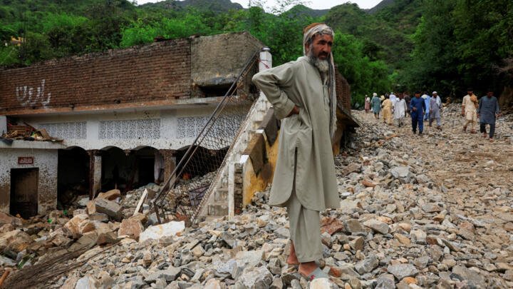 A resident stands on the pile of boulders following a storm that caused heavy rains and flooding in Pakistan's Khyber Pakhtunkhwa province, killing at least 400 people.