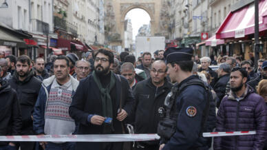 Οι παρευρισκόμενοι συγκεντρώνονται πίσω από την ταινία του εγκλήματος, όπου σημειώθηκαν τα γυρίσματα στο κέντρο του Παρισιού, στις 23 Δεκεμβρίου 2022.