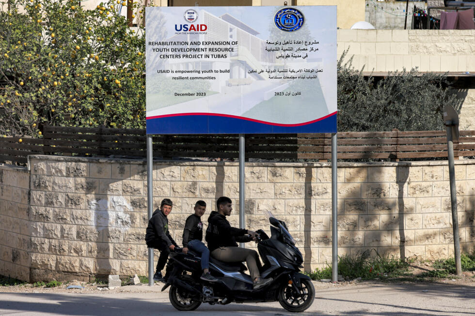 Boys ride behind a man on a scooter past a USAID-funded project for a youth center in Tubas in the north of the occupied West Bank on February 4, 2025