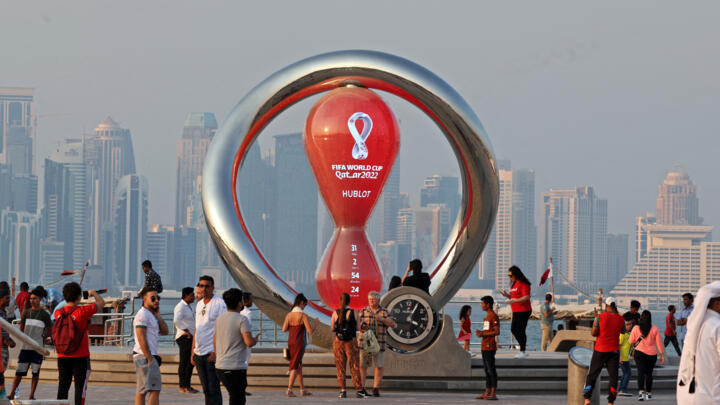 A picture taken on October 20, 2022, shows people walking past the World Cup countdown clock in the Qatari capital of Doha.