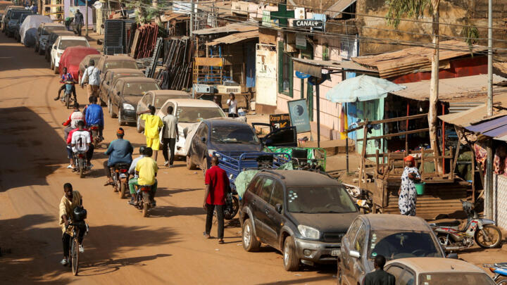 A cyclist and motorcyclists pass by cars parked on the roadside amid ongoing fuel shortages caused by a blockade imposed by al Qaeda-linked insurgents in early September, in Bamako, Mali, October 31, 2025.
