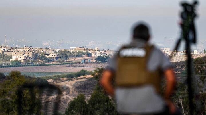 A journalist sits with a camera in the southern Israeli city of Sderot watching the skyline of the northern Gaza Strip during Israeli bombardment on October 18, 2023.