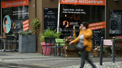 امرأة تمر من أمام موقع لإجراء فحوص كوفيد عند مطعم في دورتموند بتاريخ 6 تشرين الأول/أكتوبر 2021