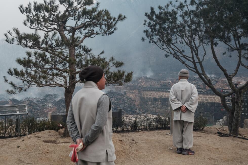 Des moines regardent les débris après que la plupart des bâtiments ont été réduits en cendres par un incendie de forêt au temple Gounsa à Uiseong, le 26 mars 2025 en Corée du Sud.