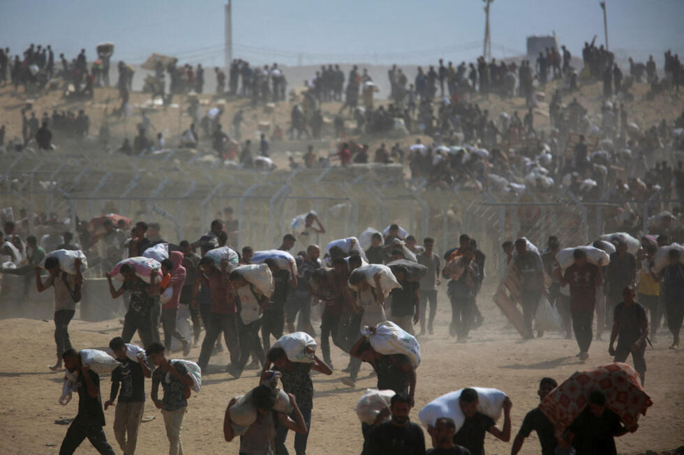 Palestinos llevan suministros de ayuda que recibieron de la Fundación Humanitaria de Gaza (GHF), respaldada por Estados Unidos, en el centro de la Franja de Gaza, el 4 de agosto de 2025.