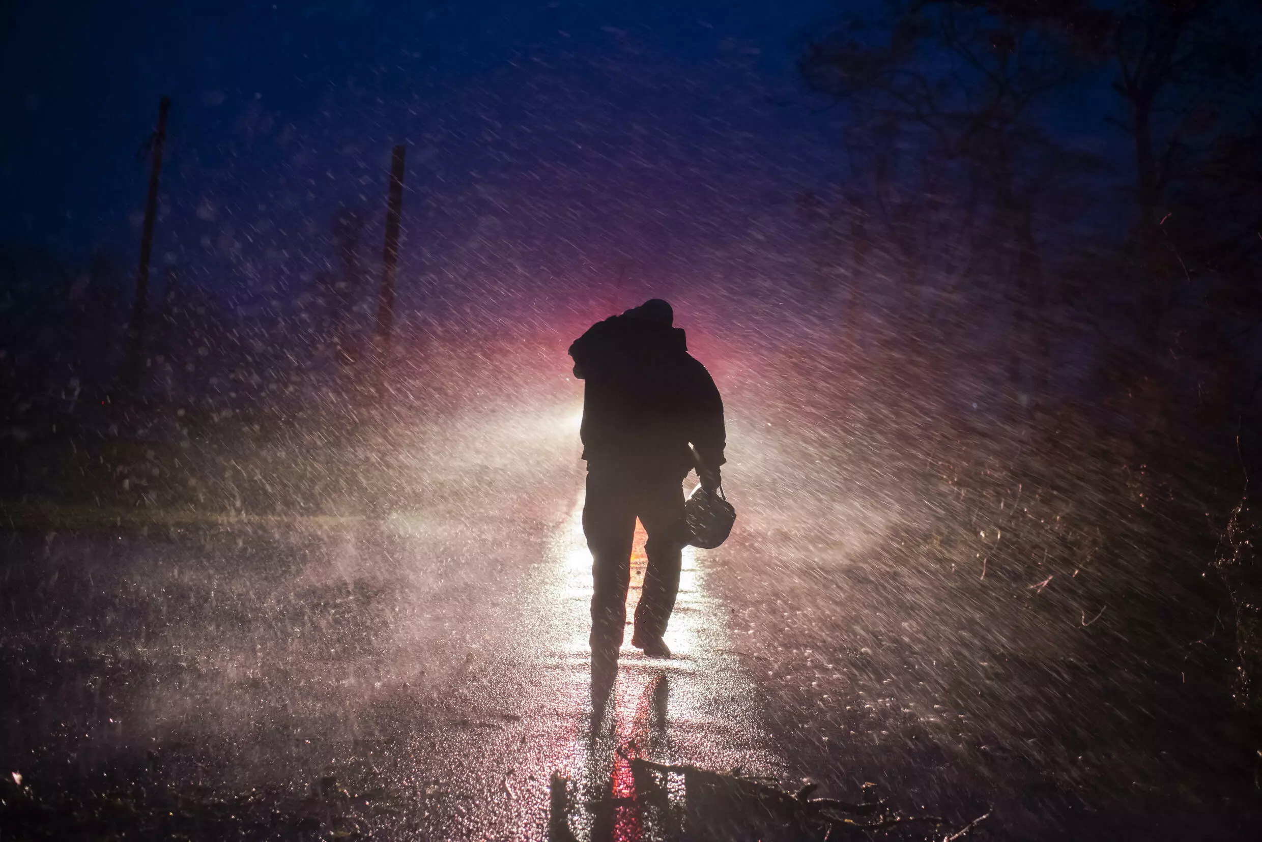 Montegut fire chief Toby Henry walks back to his firetruck after helping cut through trees on the road in Bourg, Louisiana on August 29, 2021