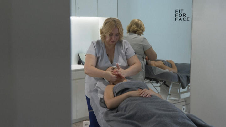 Ukrainian refugee Olena Romanova massages a client at her salon in Warsaw, Poland.