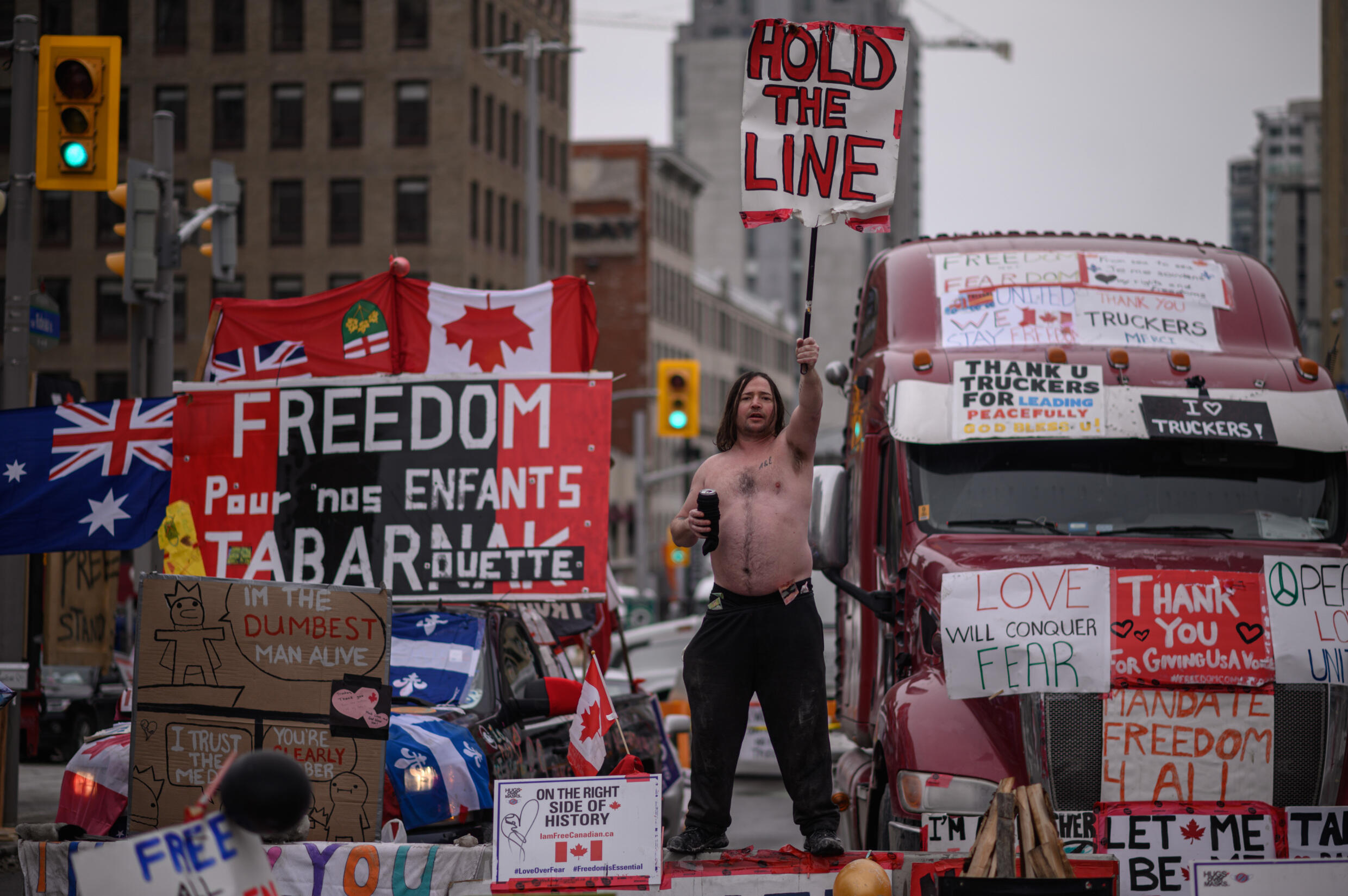 Un manifestante sostiene una pancarta durante una protesta de camioneros por las normas sanitarias contra la pandemia y el gobierno de Trudeau, frente al parlamento de Canadá en Ottawa el 16 de febrero de 2022.