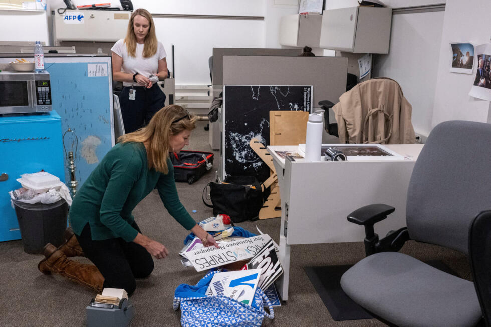 La reportera del Washington Post, Tara Copp (abajo al centro), guarda las placas con los nombres de varias organizaciones de noticias mientras ella y miembros de los medios empacan sus pertenencias en la sala de prensa del Pentágono, el miércoles 15 de octubre de 2025 en Washington.