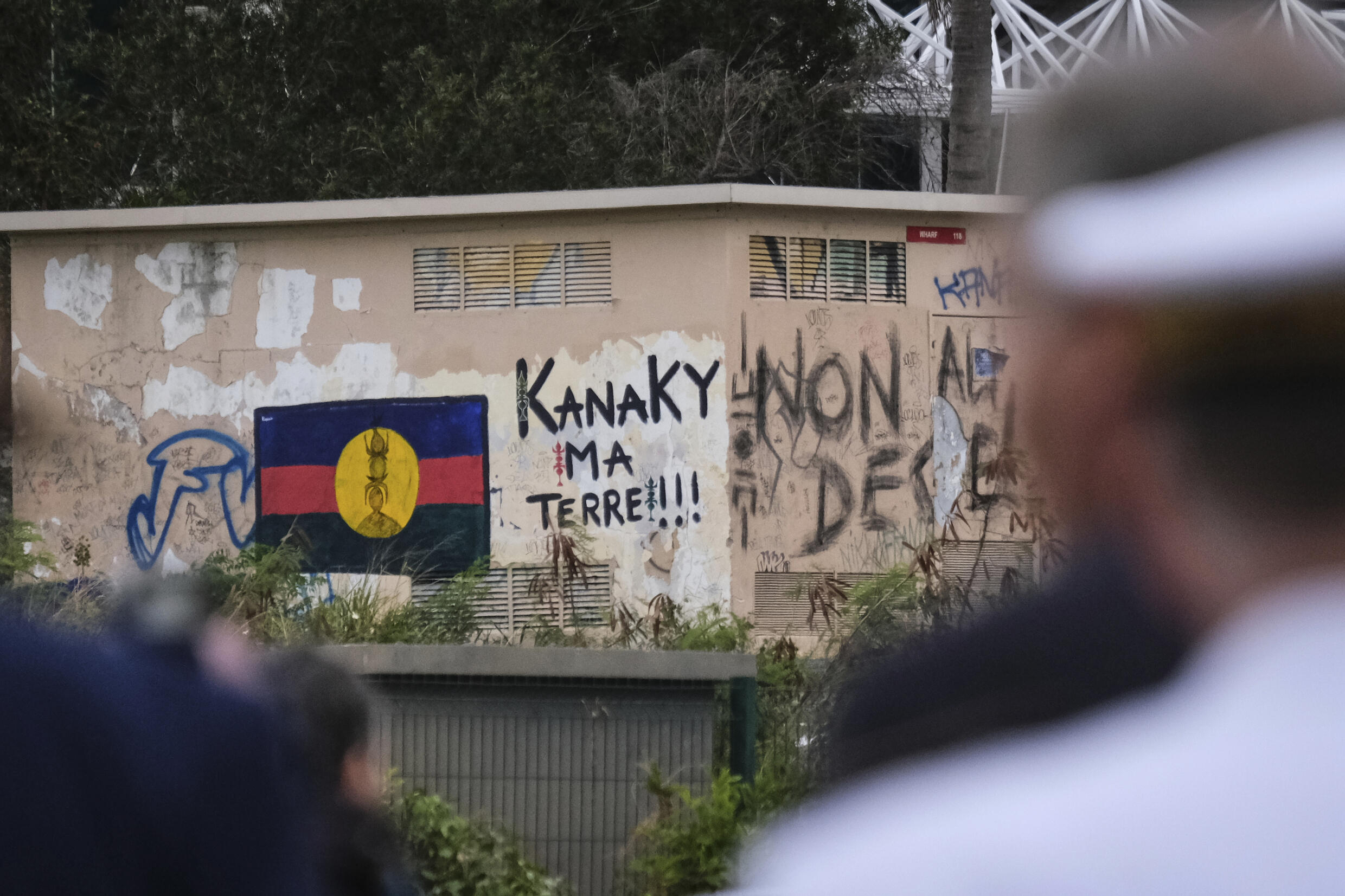 Vue d'un drapeau du FLNKS indépendantiste peint sur un mur près d'un graffiti "Kanaky ma terre!!!", le 16 octobre 2024 à Nouméa en Nouvelle-Calédonie