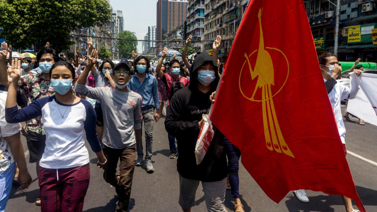 متظاهر يحمل علم اتحاد طلبة بورما خلال تظاهرة في رانغون بتاريخ 23 نيسان/أبريل 2021