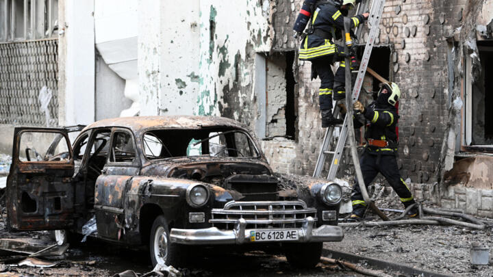 Firefighters are seen next to a burnt-out car following mass Russian drone and missile strikes in the western Ukrainian city of Lviv on July 12, 2025.