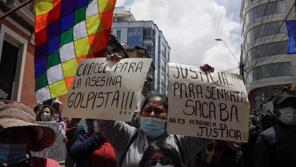 Una manifestante sostiene dos pancartas durante una protesta frente a la sede de la FELCC (Fuerza Especial de Lucha contra el Crimen) para exigir el encarcelamiento de la expresidenta interina Jeanine Áñez, en La Paz, Bolivia, el 14 de marzo de 2021.