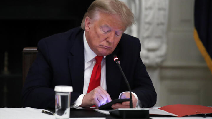 File photo: President Donald Trump looks at his phone in the State Dining Room of the White House in Washington on June 18, 2020.