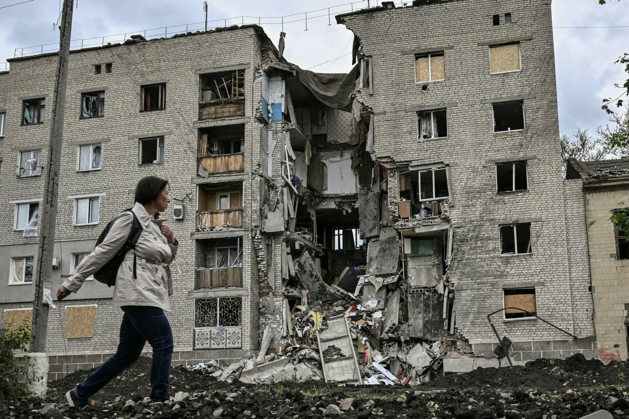 Una mujer camina junto a un edificio de apartamentos destruido en Bakhmut, en la región ucraniana oriental de Donbass, el 22 de mayo de 2022, en medio de la invasión rusa de Ucrania.