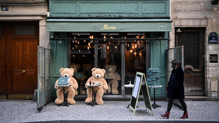 A woman walks in front of teddy bears on the terrace of a closed restaurant in Paris on March 20, 2021, the first day of the third Covid-19 lockdown in France.
