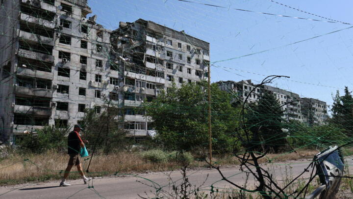 A man walks near damaged buildings and anti-drone nets in Orikhiv, Zaporizhzhia region, amid the Russian invasion of Ukraine on July 15, 2025.