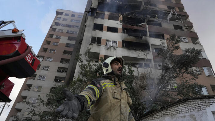 A firefighter calls out his colleagues at the scene of an explosion in a residence compound in northern Tehran, Iran on June 13, 2025.