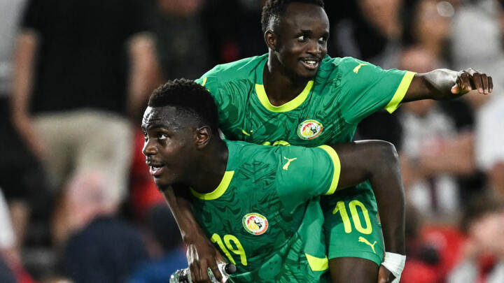 Senegal's Cheikh Sabaly (up) celebrates with Moussa Niakhate during the football match between England and Senegal at the City Ground stadium, in Nottingham, on June 10, 2025.