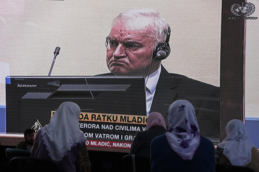 Des femmes de Srebrenica regardent une retransmission en direct du Tribunal pénal international pour l'ex-Yougoslavie (TPIY) à La Haye pour connaître le verdict du chef militaire serbe de Bosnie Ratko Mladic, à l'écran, au cimetière commémoratif de Potocari près de Srebrenica, dans l'est de la Bosnie, le 8 juin 2021.