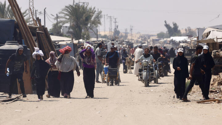 Palestinians carry humanitarian aid, they gathered after an aid drop, as they walk in the Mawasi area of Rafah in the southern Gaza Strip on August 18, 2025.
