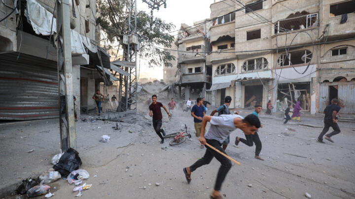 Palestinians run for cover after an Israeli strike in Bureij, in the central Gaza Strip, on October 19, 2025.