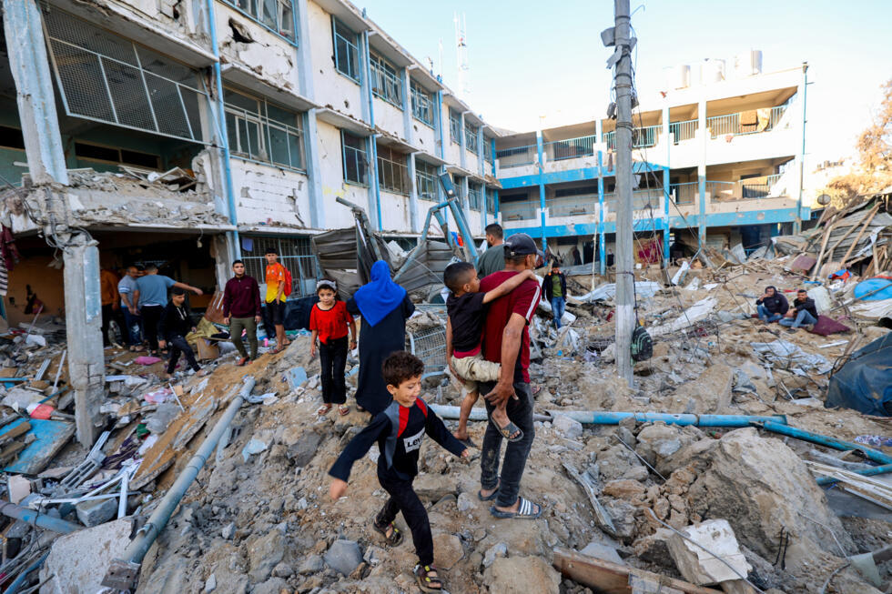 Des Palestiniens au milieu des destructions après une frappe sur une école abritant des déplacés palestiniens à Bureij, dans le centre de la bande de Gaza, le 7 mai 2025