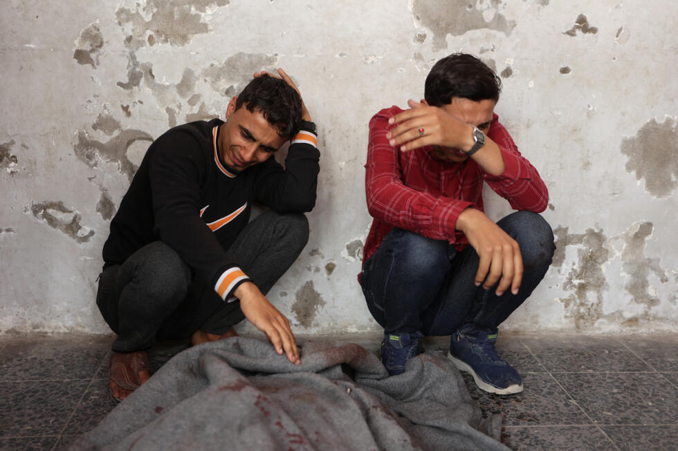 Des Palestiniens pleurent près d'un corps enveloppé dans une couverture à l'hôpital Al-Ahli, le 7 mai 2025, après une frappe israélienne dans la ville de Gaza