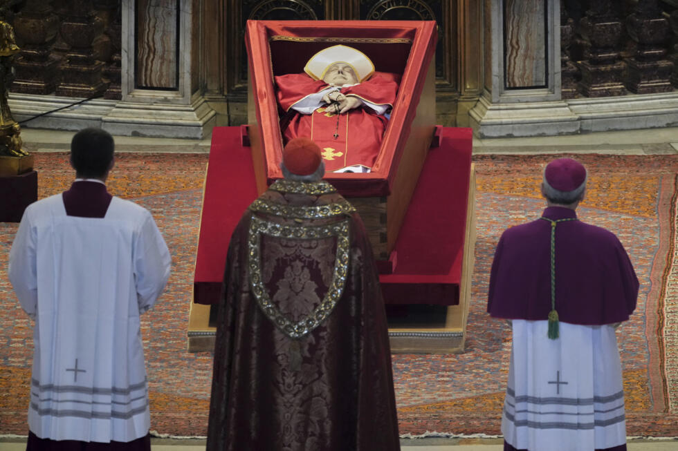 El cardenal camarlengo Kevin Joseph Farrell (centro) permanece ante el cuerpo del papa Francisco en la Basílica de San Pedro del Vaticano, el 23 de abril de 2025, donde permanecerá en capilla ardiente durante tres días.