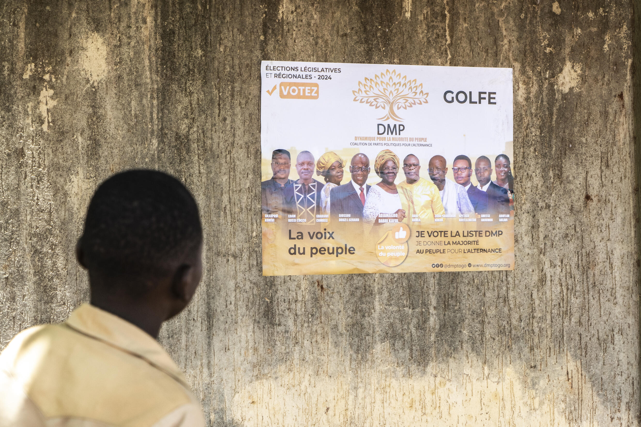 Un homme regarde une affiche électorale de la Dynamique pour la majorité du peuple (DMP), regroupement au Togo de partis politiques de l’opposition et d’organisations de la société civile, à Lomé le 24 avril 2024