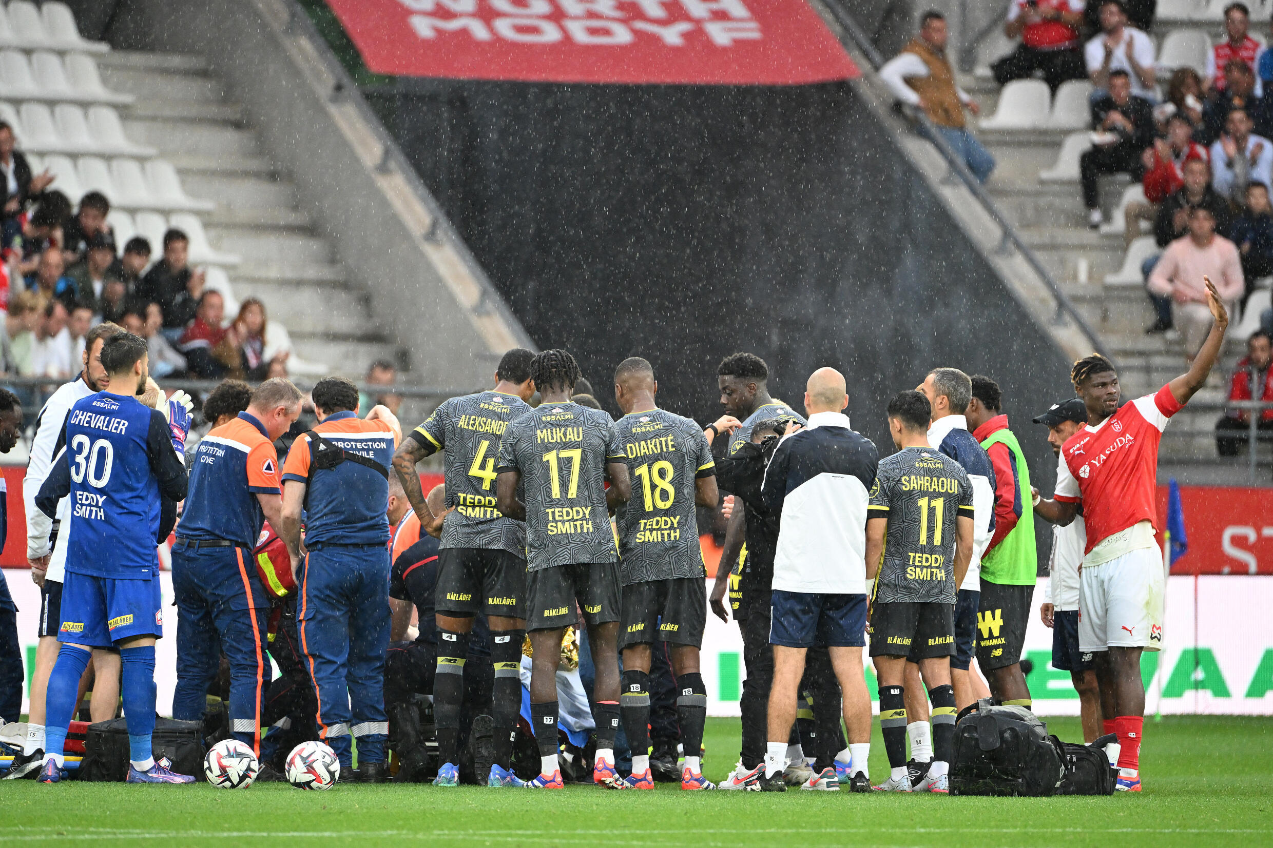 Les joueurs de Lille se tiennent autour de leur coéquipier Angel Gomes qui reçoit des soins médicaux sur le terrain du stade Auguste Delaune à Reims, le 17 août 2024.