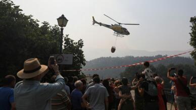 La gente observa cómo un helicóptero trabaja para contener un incendio forestal en la reserva natural Garganta de los Infiernos, durante la segunda ola de calor del año, en Jerte, España, el 17 de julio de 2022.