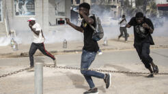 Journalists and supporters of Senegalese opposition leader Ousmane Sonko run from tear gas during a protest in Dakar on May 29, 2023.