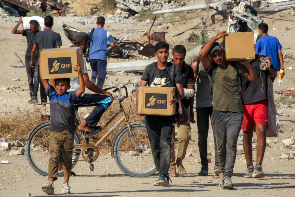 Personas caminan con cajas de ayuda humanitaria que recibieron en un centro de distribución administrado por la Fundación Humanitaria de Gaza (GHF) en el centro de la Franja de Gaza, el 22 de agosto de 2025.