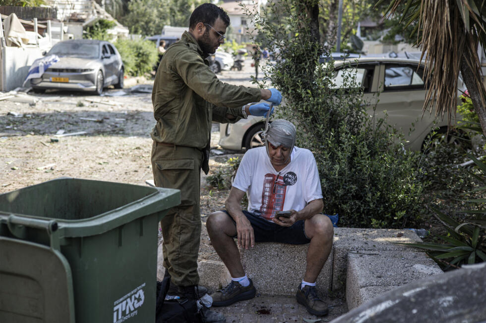 Un hombre herido lleva la cabeza vendada en un lugar alcanzado por un misil disparado desde Irán, al sur de Tel Aviv, el 14 de junio de 2025. Israel e Irán intercambiaron disparos el 14 de junio, un día después de que Israel desatara una campaña de bombardeos aéreos sin precedentes que, según Irán, afectó a sus instalaciones nucleares, «martirizó» a altos mandos y mató a decenas de civiles. Irán ha contraatacado con oleadas de ataques de drones y misiles, con una andanada de decenas de ellos iluminando los cielos de Jerusalén y Tel Aviv durante la noche, matando a tres personas e hiriendo a docenas.