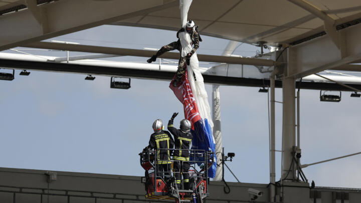 Firefighters work to rescue an air force parachutist whose canopy is jammed on the roof of the stadium prior to the European Rugby Champions Cup in TOulouse on April 6, 2025.
