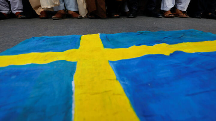 A poster depicting the Swedish flag lies on the ground, as Pakistani Shi'ite Muslim supporters of Majlis-e-Wahdat-e-Muslimeen (MWM) protest to denounce the desecration of Koran outside a mosque in the Swedish capital Stockholm, in Karachi, Pakistan July 2, 2023.