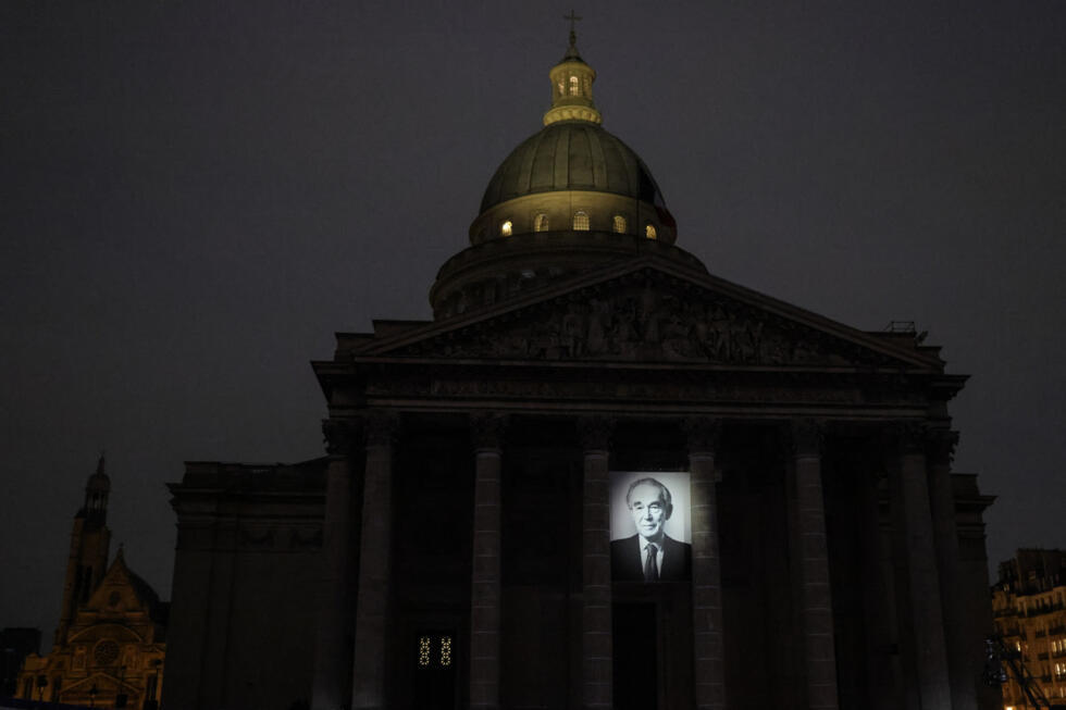 A light shines upon a portrait of late French justice minister Robert Badinter on the facade of the Panthéon during his induction ceremony in Paris on October 9, 2025.