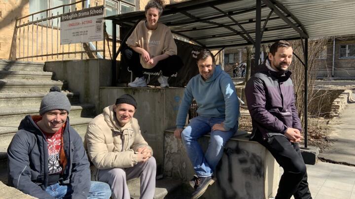 Alex Borovensky, Tetiana Shelepko and their friends sit in front of the ProEnglish Theatre in Kyiv, on March 20, 2022.
